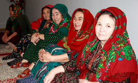 Elderly women in traditional Turkmen clothes sitting in the room